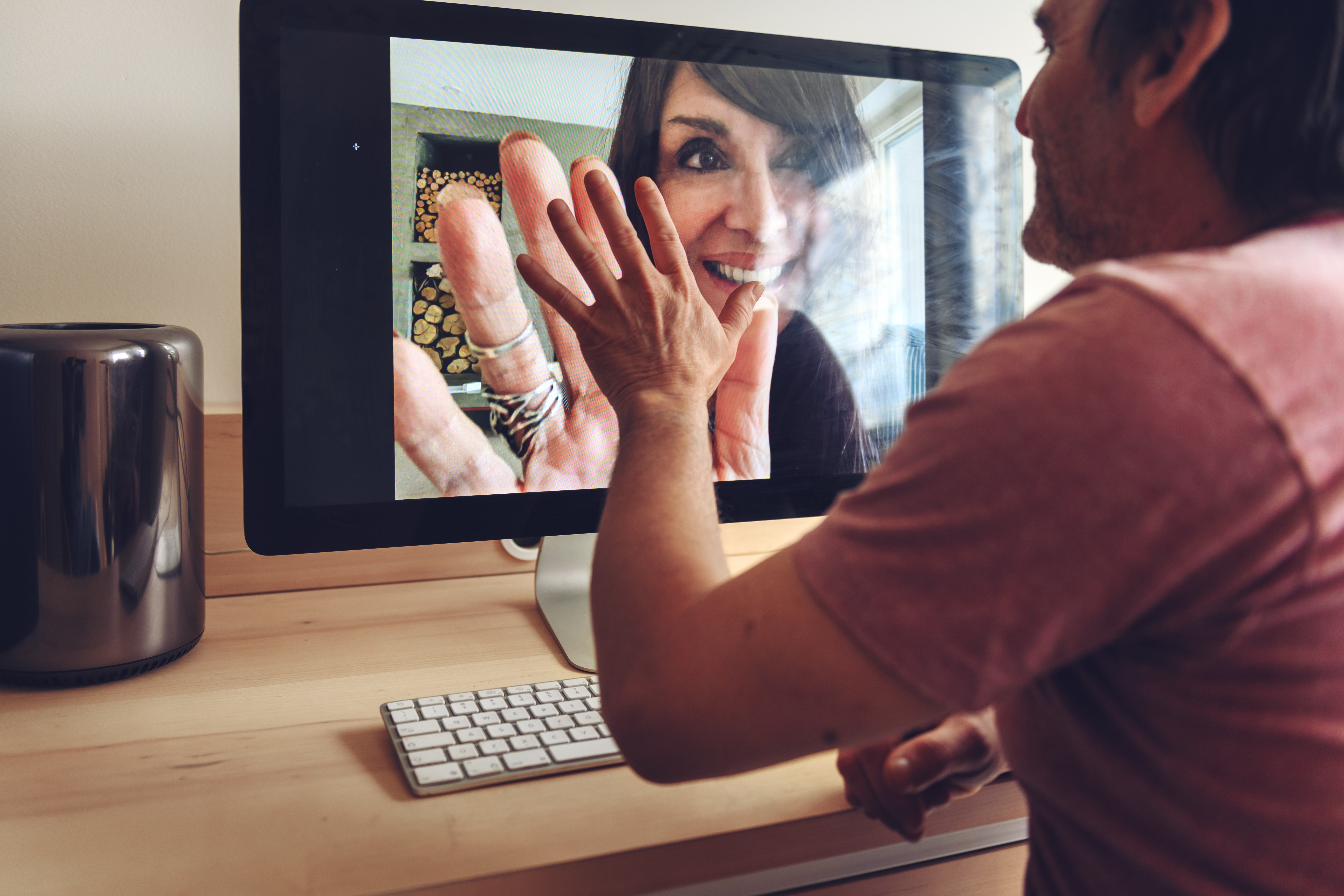 Foto di mani che si toccano sullo schermo durante una video call tra due persone